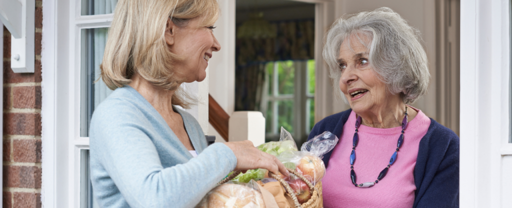 femme qui apporte courses à personne âgée sourire